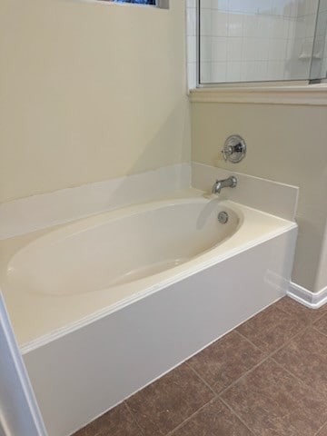 bathroom with tile patterned floors and a bath