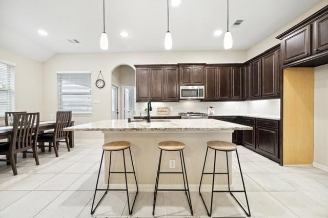 kitchen featuring decorative light fixtures, sink, a kitchen island with sink, and vaulted ceiling