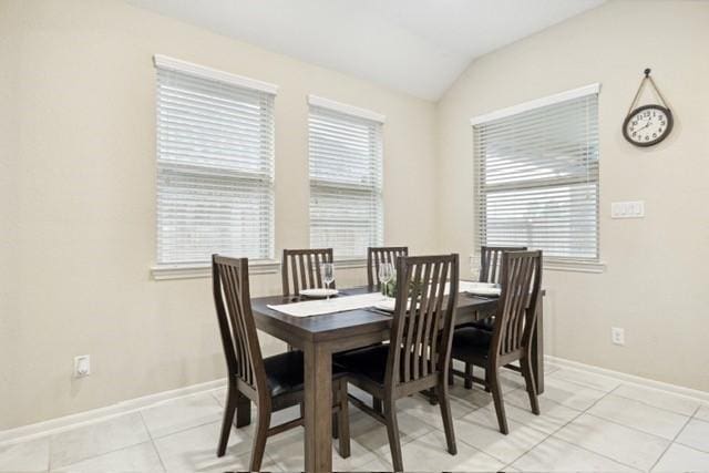 dining space featuring light tile patterned floors and vaulted ceiling