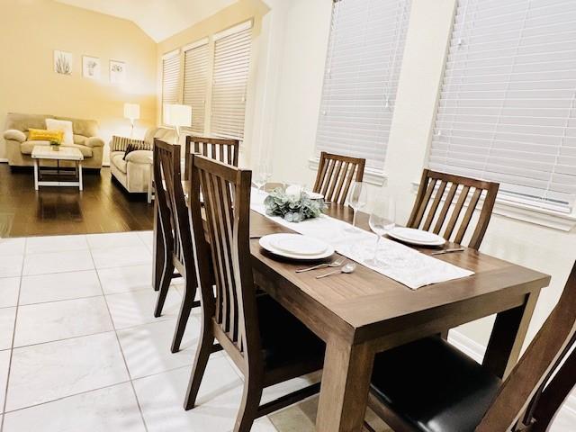 dining space with light hardwood / wood-style flooring and vaulted ceiling