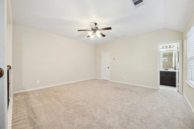 unfurnished bedroom featuring light carpet, vaulted ceiling, ensuite bath, and ceiling fan