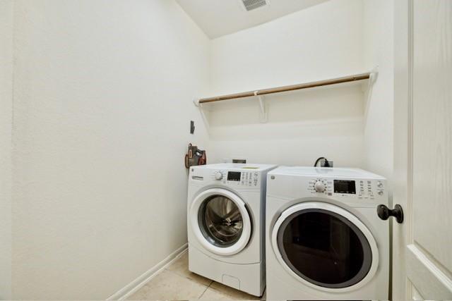 clothes washing area with light tile patterned floors and separate washer and dryer