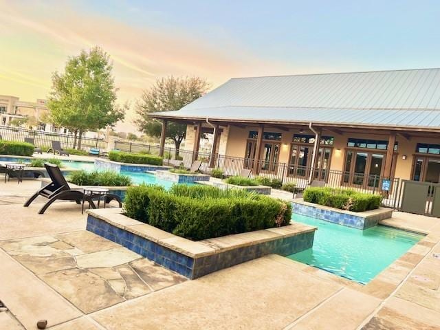 pool at dusk featuring a patio and french doors