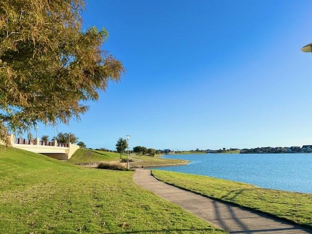 surrounding community with a lawn and a water view