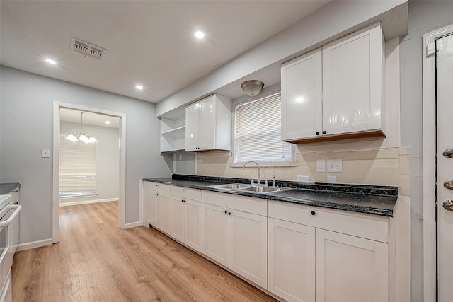 kitchen with white cabinets, sink, light hardwood / wood-style flooring, tasteful backsplash, and a chandelier