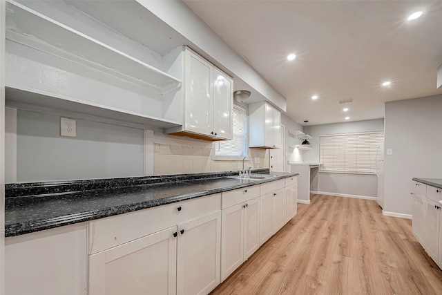 kitchen with sink, tasteful backsplash, light hardwood / wood-style flooring, pendant lighting, and white cabinets