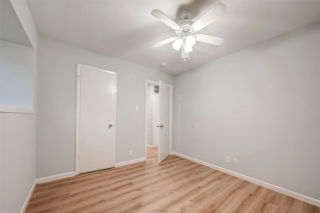 unfurnished bedroom featuring ceiling fan, light wood-type flooring, a textured ceiling, and a closet