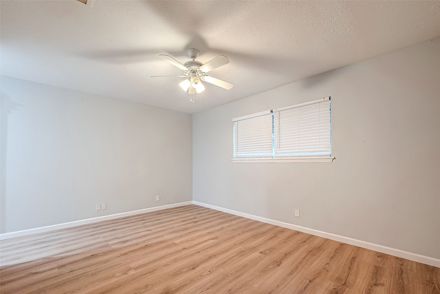 empty room with ceiling fan, light wood-type flooring, and a textured ceiling