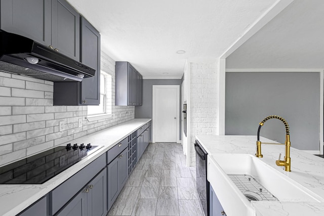 kitchen with black appliances, gray cabinets, light stone counters, and sink