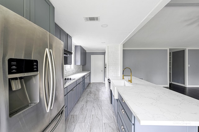 kitchen with gray cabinets, black electric stovetop, decorative backsplash, stainless steel refrigerator with ice dispenser, and sink