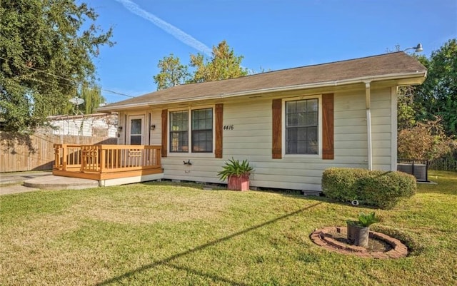 rear view of property featuring a yard, a wooden deck, and central AC