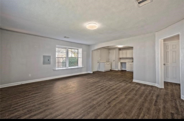 unfurnished living room featuring a textured ceiling, dark hardwood / wood-style flooring, and electric panel