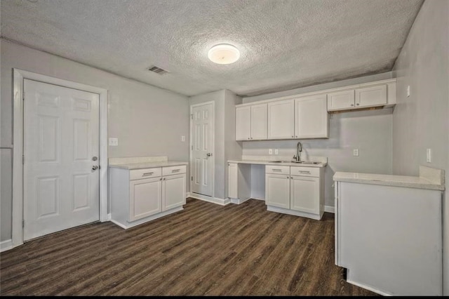 kitchen with sink, dark hardwood / wood-style flooring, white cabinetry, and a textured ceiling