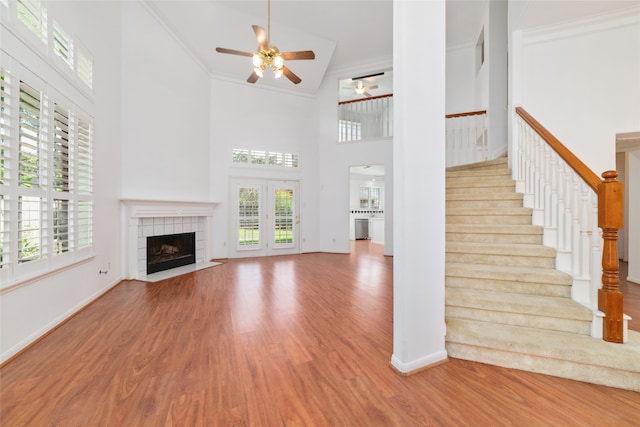 unfurnished living room featuring high vaulted ceiling, crown molding, ceiling fan, a fireplace, and light hardwood / wood-style floors