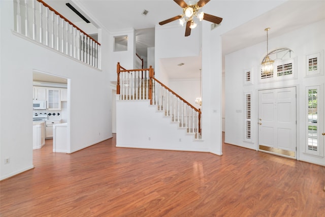 entrance foyer with a high ceiling, ceiling fan with notable chandelier, and hardwood / wood-style flooring