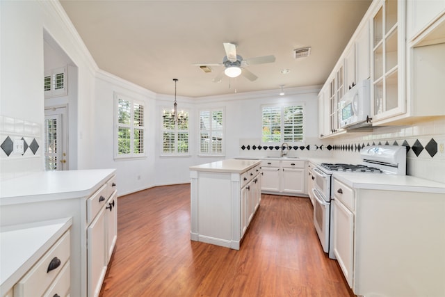 kitchen featuring white appliances, white cabinets, tasteful backsplash, decorative light fixtures, and a kitchen island