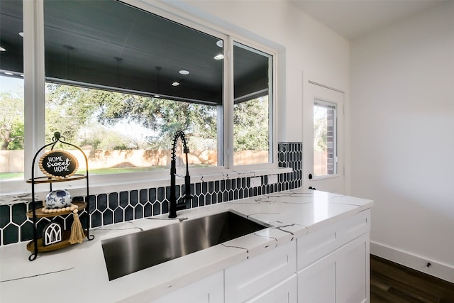 kitchen with white cabinets, dark hardwood / wood-style floors, light stone countertops, and sink