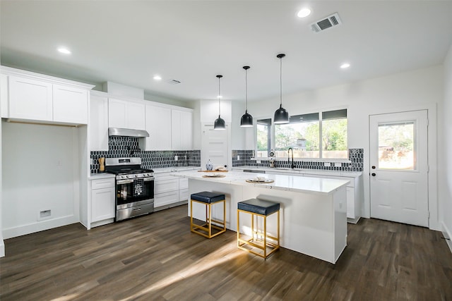 kitchen with stainless steel range, dark hardwood / wood-style flooring, white cabinetry, and a kitchen island