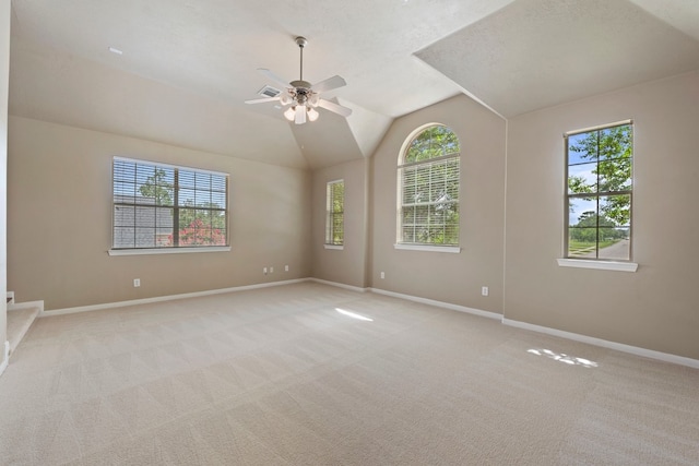 carpeted empty room with lofted ceiling, ceiling fan, and a healthy amount of sunlight