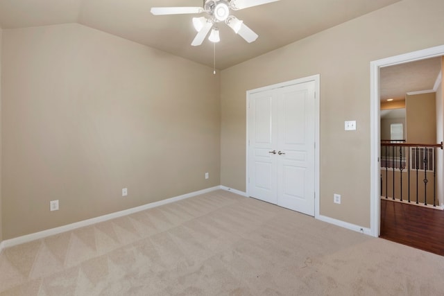 unfurnished bedroom with vaulted ceiling, light colored carpet, ceiling fan, and a closet