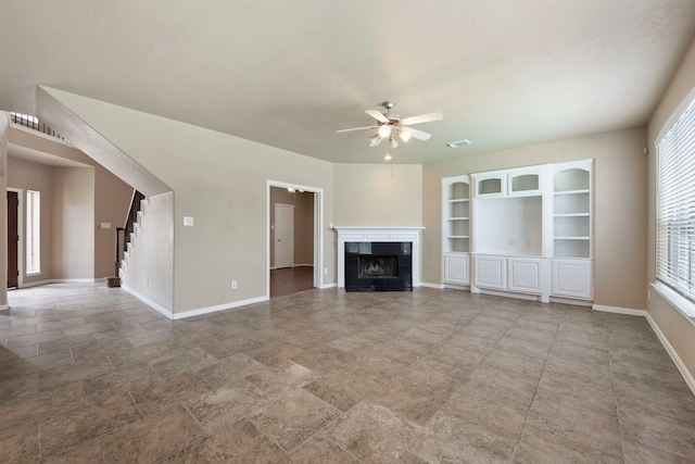 unfurnished living room featuring built in shelves, ceiling fan, and a tile fireplace