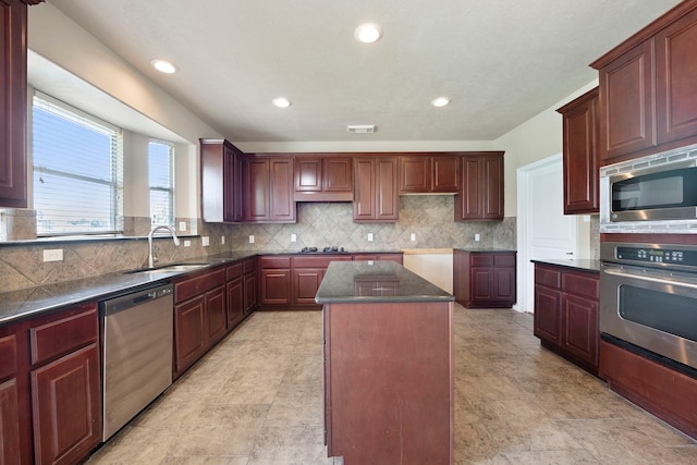 kitchen with sink, backsplash, stainless steel appliances, and a center island