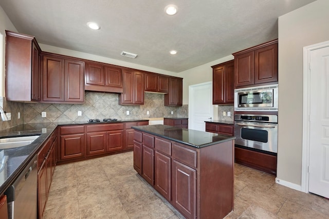 kitchen with a kitchen island, sink, backsplash, dark stone counters, and stainless steel appliances