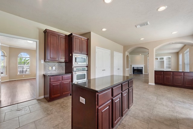 kitchen featuring appliances with stainless steel finishes, a center island, a textured ceiling, and backsplash