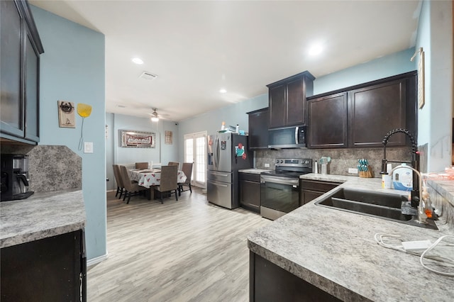 kitchen featuring sink, light hardwood / wood-style flooring, decorative backsplash, ceiling fan, and appliances with stainless steel finishes