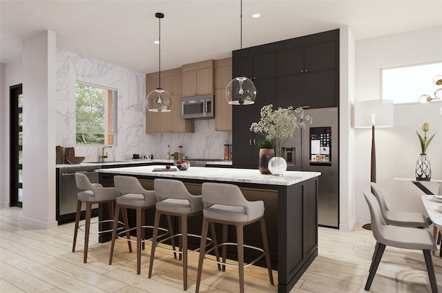 kitchen featuring appliances with stainless steel finishes, a breakfast bar, light hardwood / wood-style flooring, a center island, and hanging light fixtures