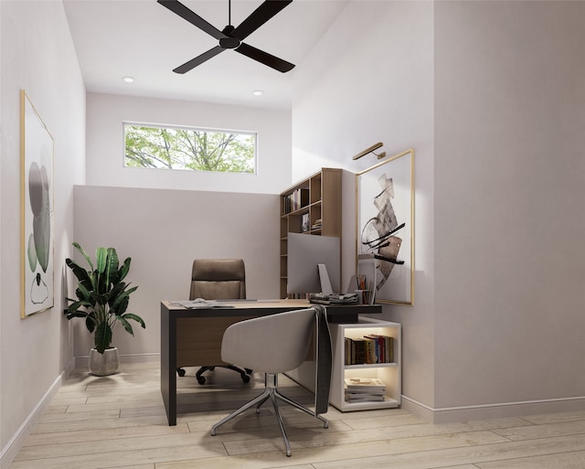 home office featuring ceiling fan, a towering ceiling, and light hardwood / wood-style floors