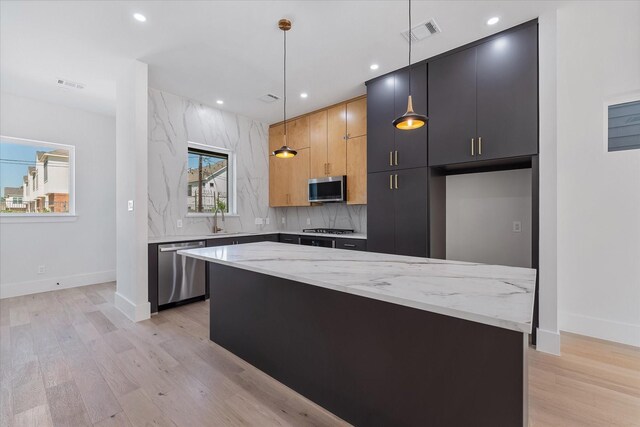 kitchen featuring light stone countertops, light wood finished floors, a kitchen island, and stainless steel appliances
