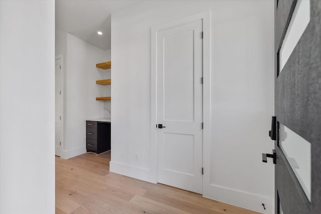 hall featuring light wood finished floors, baseboards, and recessed lighting