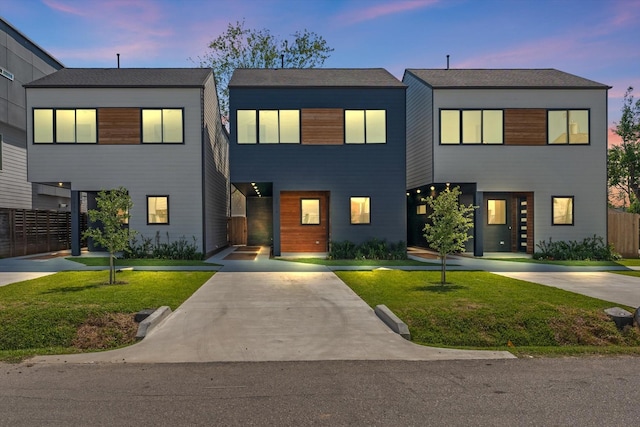 view of front of home featuring concrete driveway, a yard, and fence