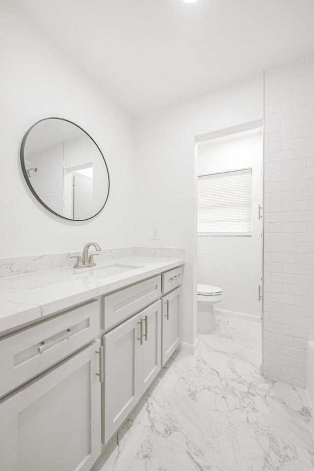 bathroom with vanity, a tub to relax in, and toilet