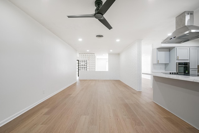 unfurnished living room with ceiling fan, brick wall, and light wood-type flooring