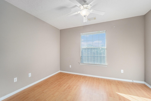 spare room with light wood finished floors, visible vents, baseboards, a textured ceiling, and a ceiling fan