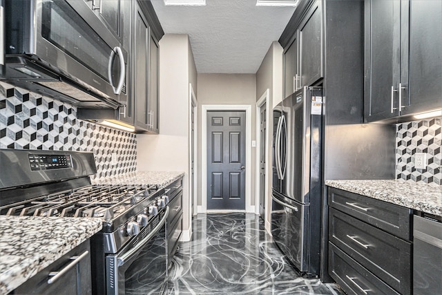 kitchen with light stone counters, marble finish floor, stainless steel appliances, and dark cabinetry