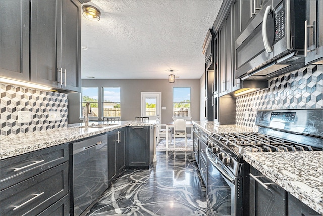 kitchen featuring a healthy amount of sunlight, appliances with stainless steel finishes, light stone countertops, and a sink