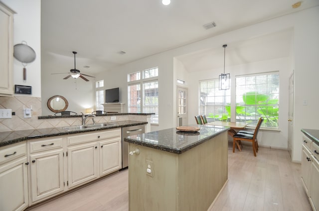 kitchen featuring pendant lighting, a healthy amount of sunlight, dark stone counters, and light hardwood / wood-style flooring