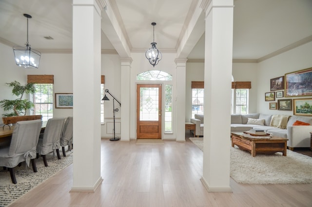 entryway with decorative columns, a wealth of natural light, crown molding, and light wood-type flooring