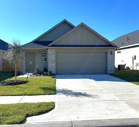 view of front facade featuring central AC unit, a garage, and a front lawn