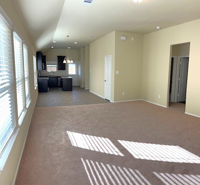 unfurnished living room with a notable chandelier, dark carpet, and vaulted ceiling