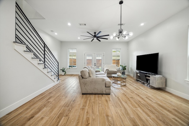 living room with french doors, light hardwood / wood-style floors, and ceiling fan with notable chandelier