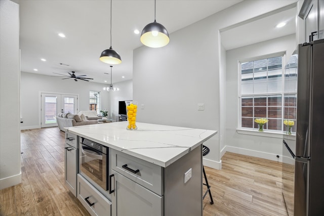 kitchen featuring appliances with stainless steel finishes, french doors, decorative light fixtures, a center island, and light hardwood / wood-style floors