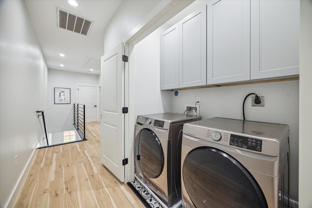 laundry area with washer and dryer, light hardwood / wood-style flooring, and cabinets