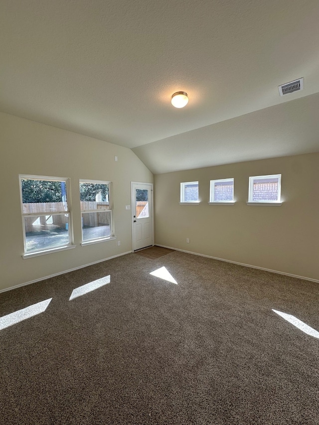 bonus room featuring plenty of natural light, vaulted ceiling, and dark colored carpet