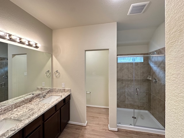 bathroom with hardwood / wood-style flooring, vanity, a shower with shower door, and a textured ceiling