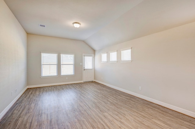 unfurnished room with light hardwood / wood-style floors and vaulted ceiling