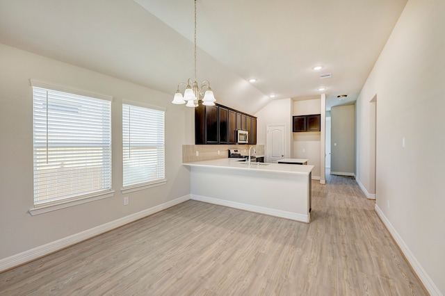 kitchen featuring lofted ceiling, hanging light fixtures, a notable chandelier, light hardwood / wood-style floors, and kitchen peninsula